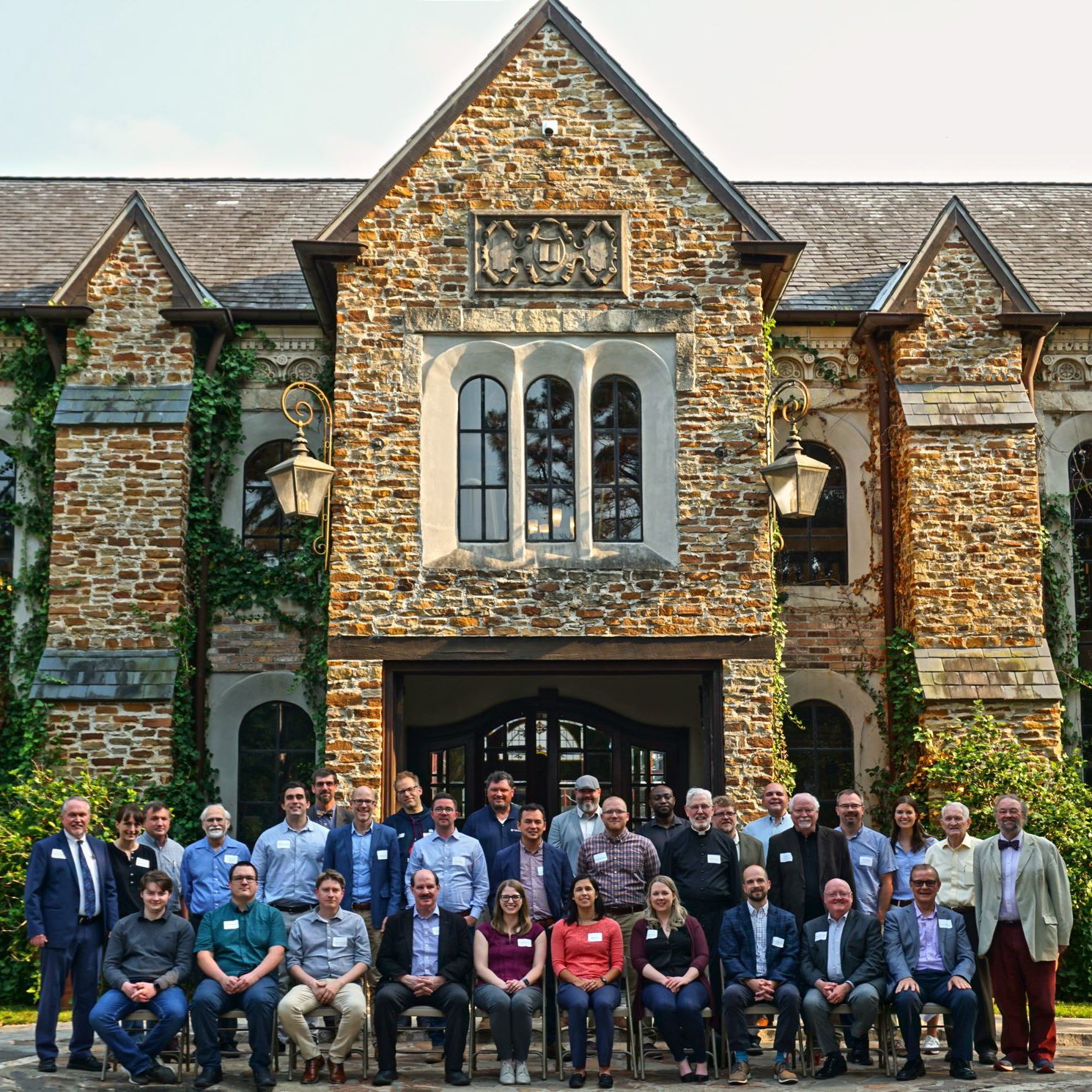 Large group photo in front of a stone building